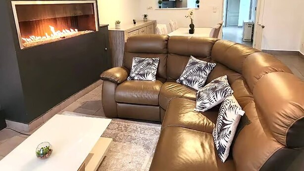 A modern living room with a brown leather sofa, zebra-patterned cushions, a glass coffee table, and a built-in fireplace. - Welcome to our Mouscron Cocoon (Mouscron)