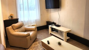 A living room with a leather sofa, a TV mounted on the wall, a small table with a remote control, and a decorative bowl on the table. - Welcome to our Mouscron Cocoon (Mouscron)