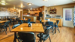 Un restaurant avec des tables et des chaises en bois, un espace cuisine et un comptoir où sont exposés divers articles.