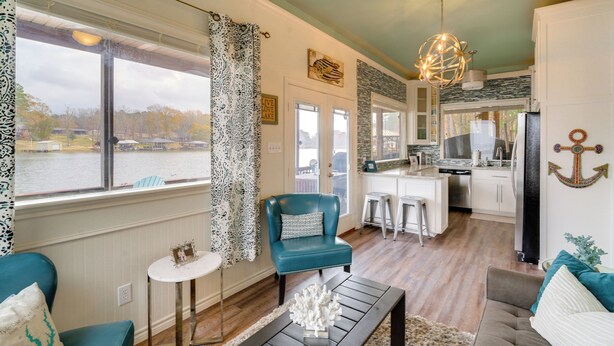 A spacious living area with a view of a lake, a kitchen with modern appliances, and a dining area with bar stools. - Wake Up on the Water! Lake Tyler East Hideaway (Troup)