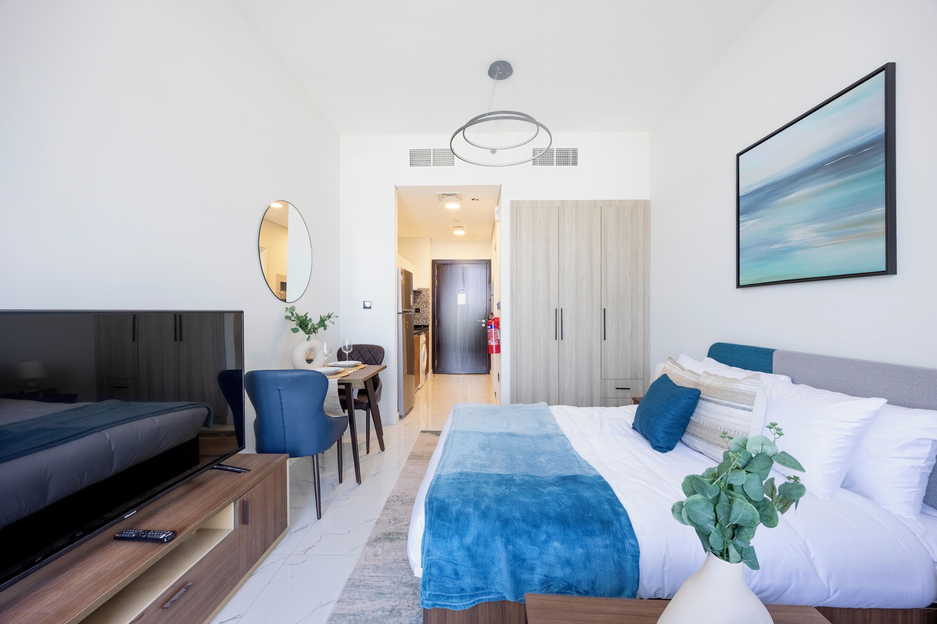 A modern hotel room with a bed, a desk, a chair, a TV, and a large window.
