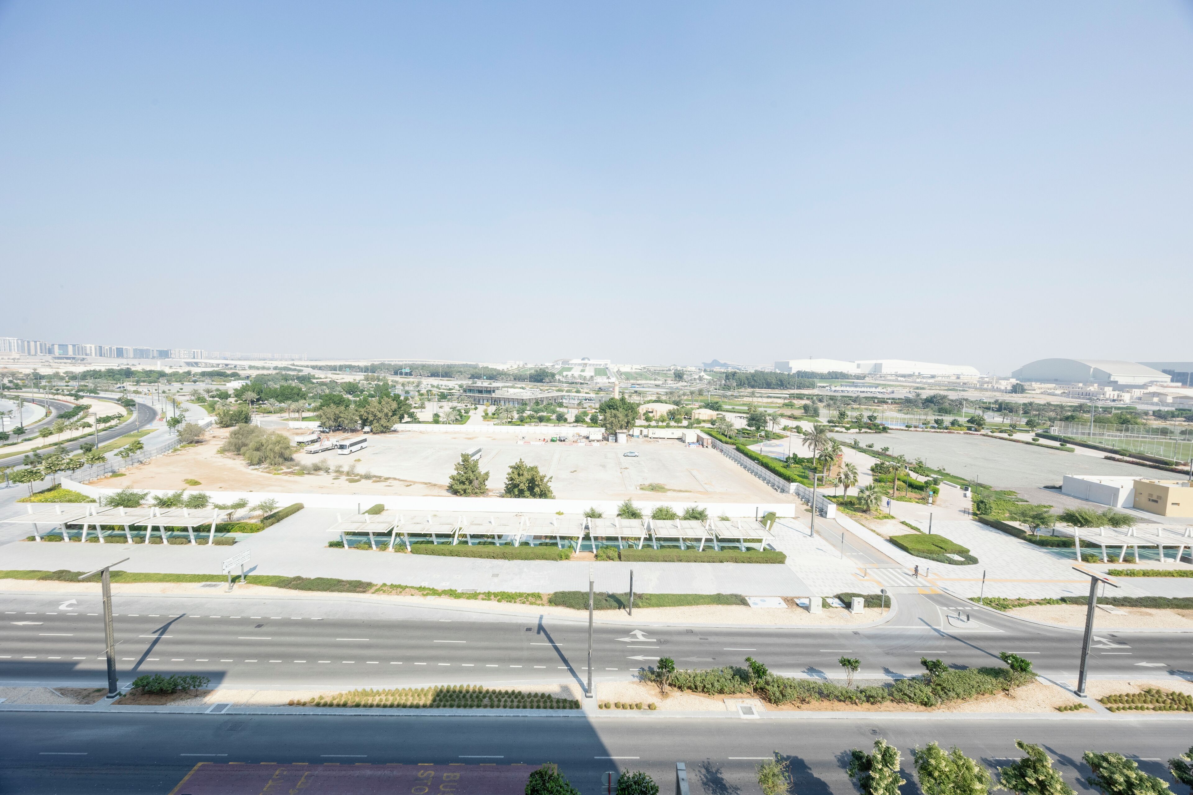 An aerial view of a large, open parking lot with multiple lanes and a few buildings in the background.