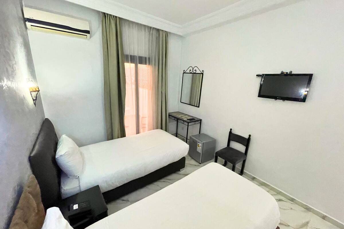 A hotel room with two beds, a TV, a desk, and a chair.