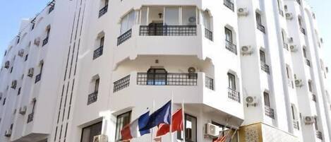 A multi-story hotel with balconies, a sign for 'LAPERLE', and flags.