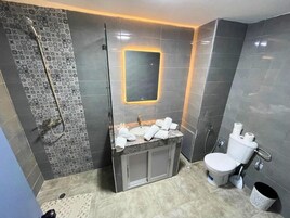 Casa de banho moderna com chuveiro, pia e sanita.