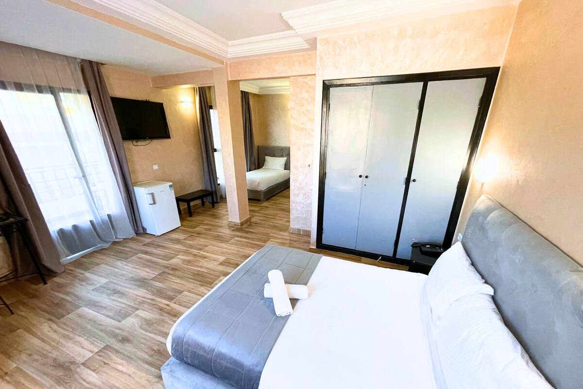 A hotel room with a large bed, a wardrobe, a television, and a small table.