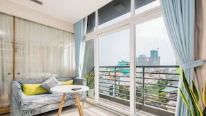 Ein modernes Wohnzimmer mit einer Couch, einem kleinen runden Tisch und einem großen Fenster mit Blick auf die Stadt.