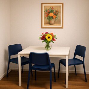 Une table à manger avec un vase de fleurs et deux chaises.