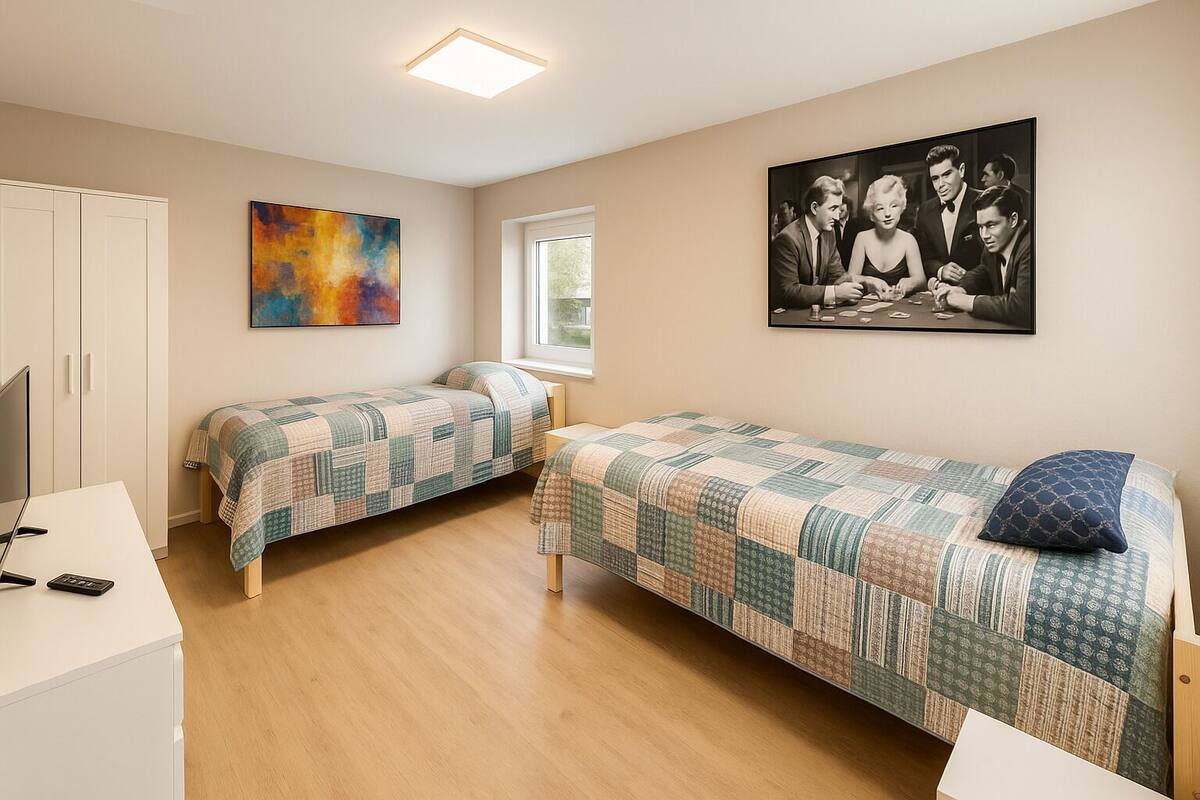 Une chambre avec deux lits simples, un bureau, une chaise, une télévision et une fenêtre.