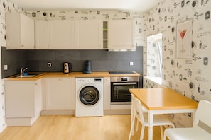 Une cuisine compacte  équipée d’un lave-linge, d’un four et d’une machine à café.