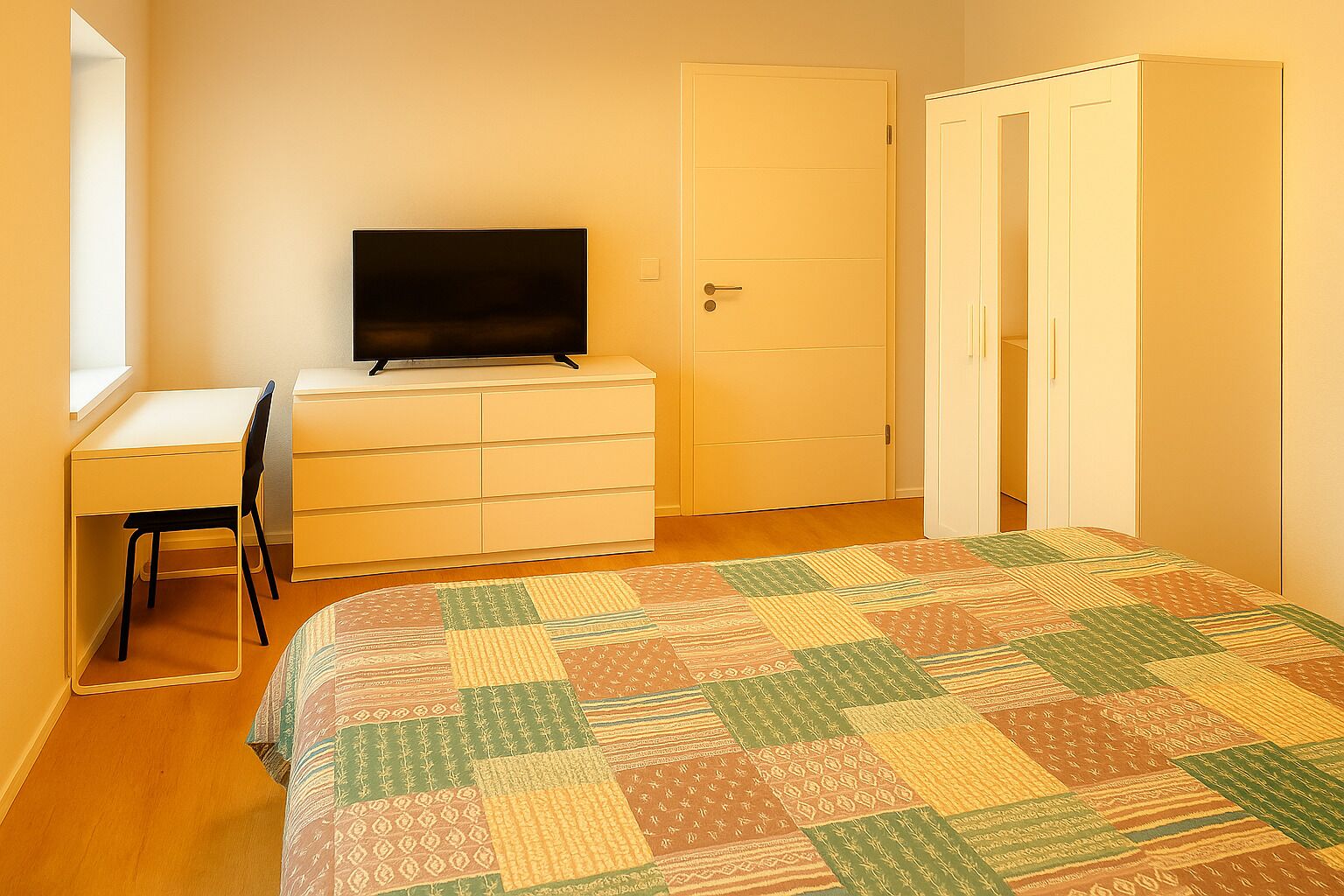 A bedroom with a bed, a desk, a chair, a television, and a wardrobe.