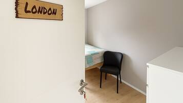A room with a bed, a chair, a white dresser, and a wall sign that reads "LONDON".