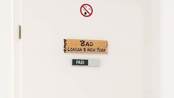 Una puerta blanca con un cartel de 'No Fumar', un cartel de 'Bad London & New York' y un cartel que dice 'Gratis'.