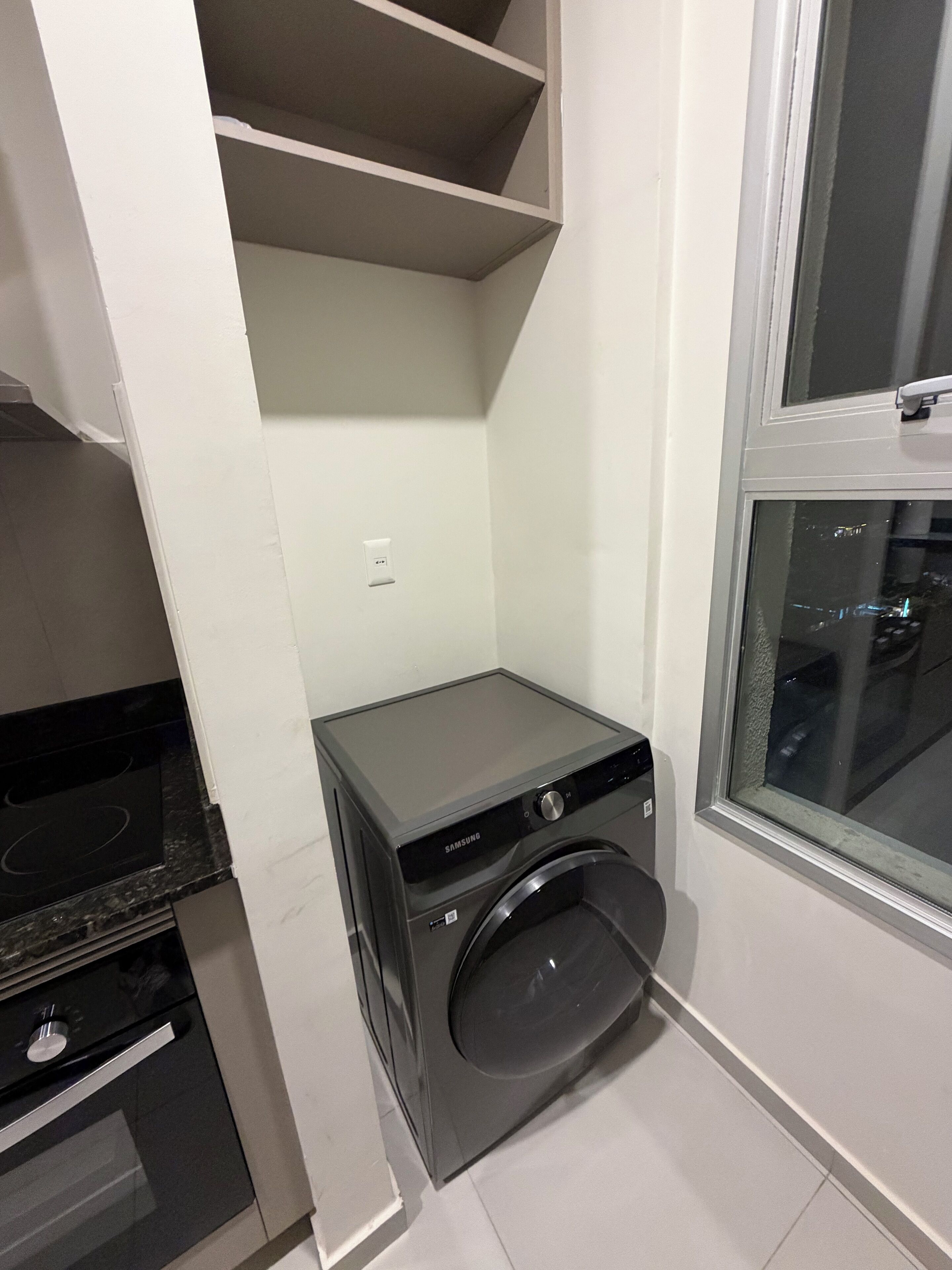 Cuina compacta amb rentadora i assecadora integrades, fogó i finestra amb vista.