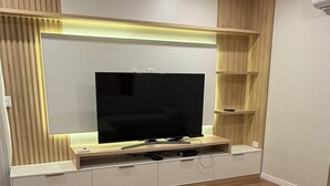 A modern living room with a flat-screen TV, built-in shelving, and a sofa.