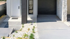 A modern two-story house with a garage, a balcony, and a stone facade.