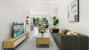 A modern living room with a sofa, coffee table, and TV on a wooden console.