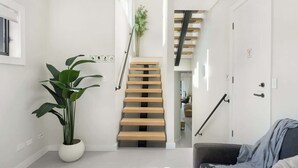 A modern interior with a staircase, a potted plant, and a sofa.