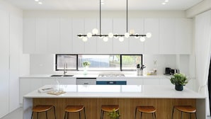 A modern kitchen with a central island, bar stools, and a window providing a view.