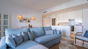 A modern living room with a light blue sofa, wicker ottomans, and pendant lights. - Modern Luxurious 3-Bedroom Residence with Resort Amenities (Benahavís)