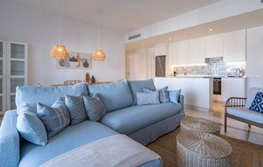 Ein modernes Wohnzimmer mit einem hellblauen Sofa, Korbsesseln und Pendelleuchten.