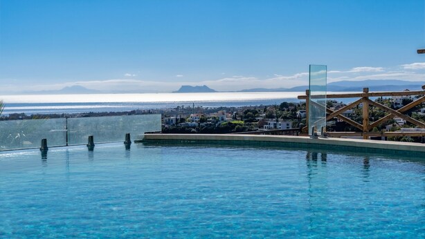 A clear blue pool with a view of the sea and distant mountains. - Modern Luxurious 3-Bedroom Residence with Resort Amenities (Benahavís)