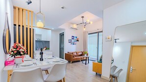 Et moderne spiseområde med en træafskærmning, et spisebord dækket til to personer, og en sofa i baggrunden.