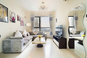A modern living room with a sofa, coffee table, TV, and artwork on the walls. - MASTERI Premier Residence (Thao Dien)