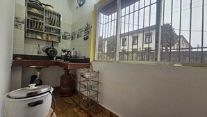 Une cuisine compacte équipée d’une cuisinière à gaz, d’une bouteille de gaz, d’un évier et d’une fenêtre donnant sur un immeuble.