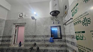 Une salle de bain avec un mur en marbre, une douche, un miroir et des toilettes.