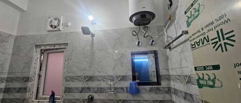 A bathroom with a marble wall, a shower, a mirror, and a toilet.