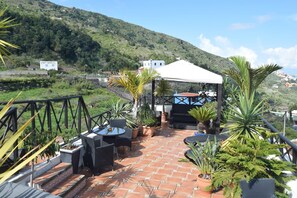 A terrace with outdoor seating, potted plants, and a white tent structure. - English-Style Apartment only for Adults (Icod de los Vinos, Tenerife)