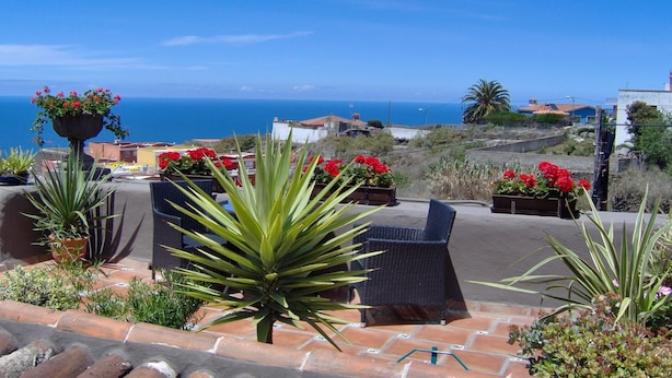 An outdoor seating area with patio furniture, potted plants, and a view of the sea. - English-Style Apartment only for Adults (Icod de los Vinos, Tenerife)