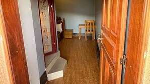 Un couloir étroit, avec des portes en bois et un escalier menant à une pièce.