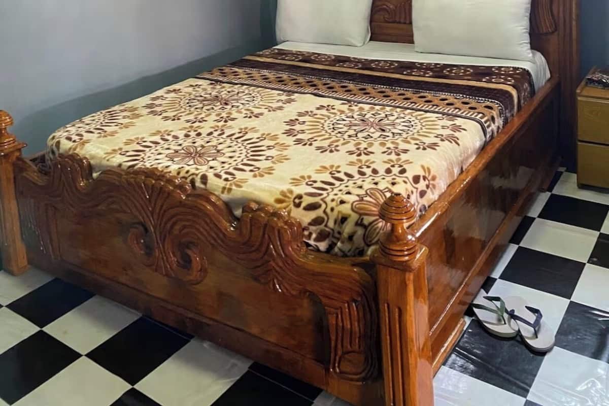 A wooden bed with a patterned bedspread, a nightstand, and a checkered floor.
