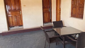 Une pièce avec une table en verre et des chaises en osier, des portes en bois et un tapis rouge menant à un escalier.