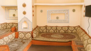 Une pièce à l’aménagement traditionnel, avec un ensemble de canapés, des panneaux décoratifs et un téléviseur fixé au mur.