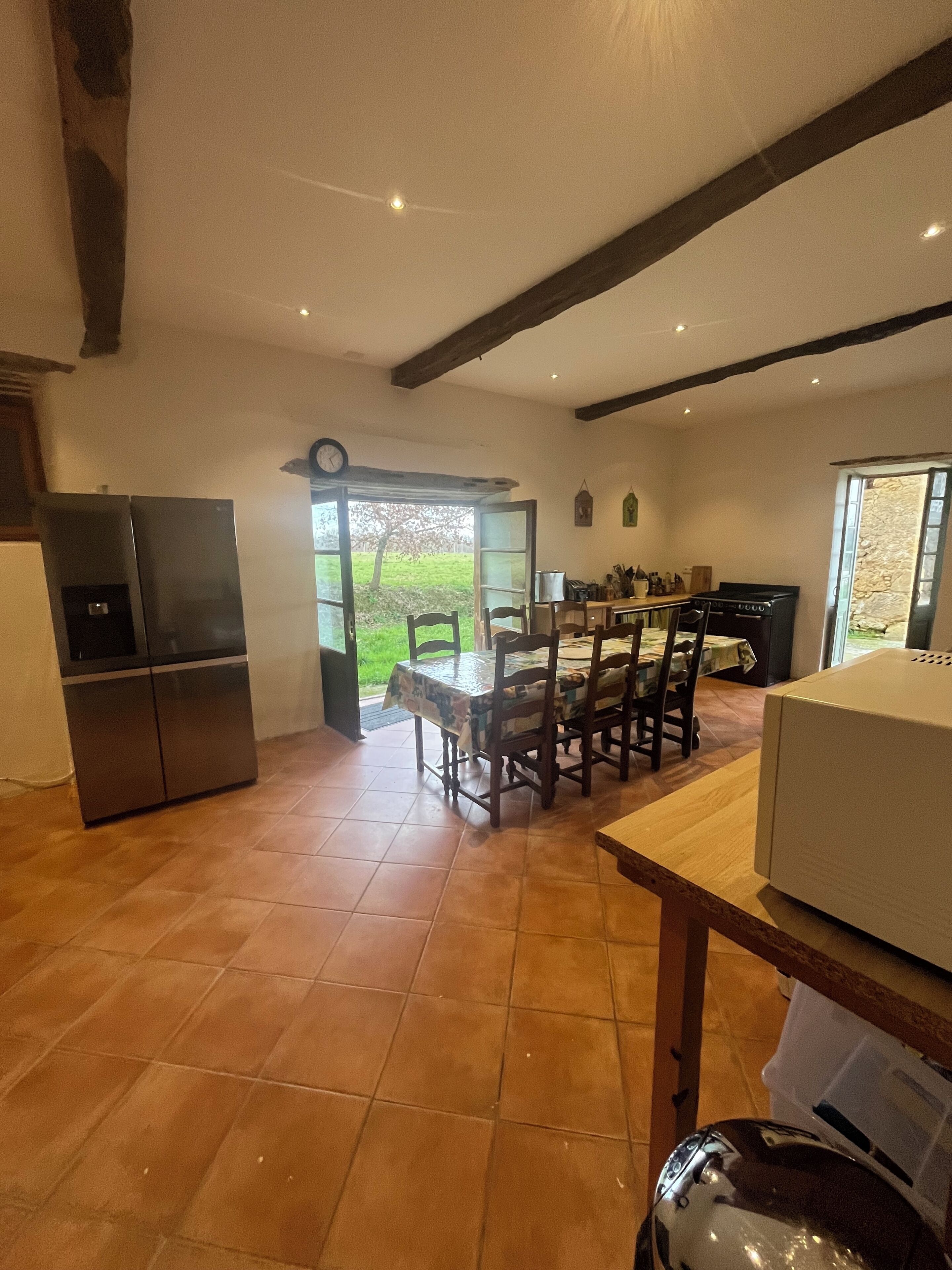 A kitchen with a dining area, a refrigerator, a stove, and a window overlooking a garden.