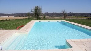 Una piscina rectangular amb una superfície d'aigua blava i transparent, envoltada d'un solàrium pavimentat.