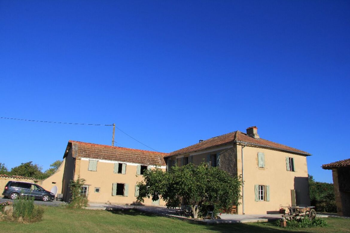 A two-story house with a tiled roof, a small garden, and a parked car.