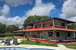 A two-story building with a red and white exterior, a covered patio, and a swimming pool.