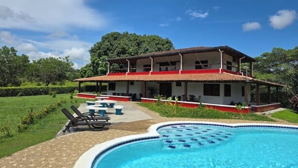 Une maison à deux étages avec une piscine, un espace salon extérieur et un jardin.