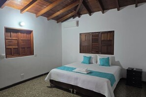 A bedroom with a bed, two pillows, a nightstand, and a wooden ceiling.