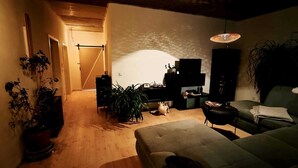 A cozy living room with a sofa, a TV, and a lamp. There are plants and a wooden floor. - Stylish time-out near Nuremberg/Herzogenaurach (Hagenbüchach)