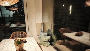 A dining area with a tiled table, wicker chairs, and a cushioned bench. - Stylish time-out near Nuremberg/Herzogenaurach (Hagenbüchach)