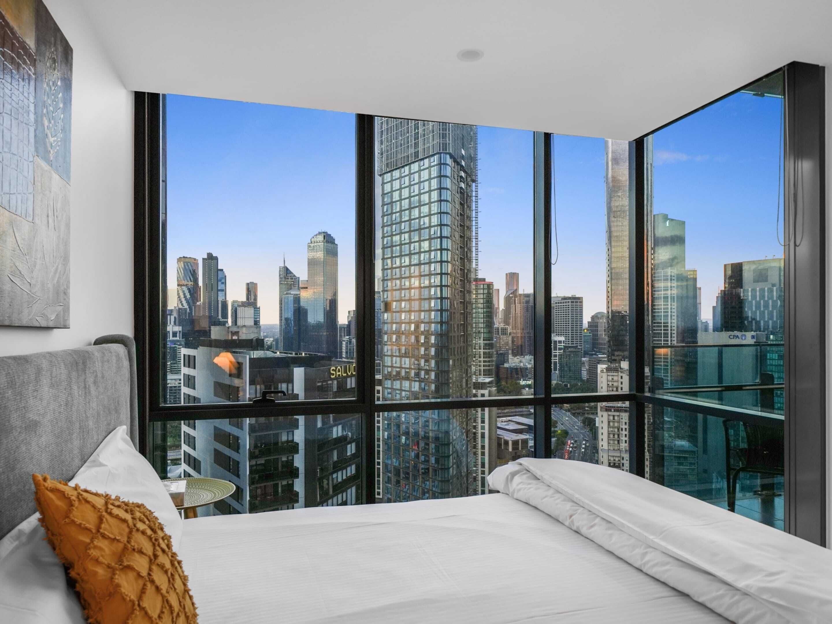 A bedroom with a large window offering a city skyline view.