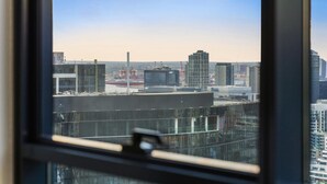 A cityscape through a window with a view of various buildings, including a tall skyscraper and a construction site. - Stunning 2-bed Apartment With City Views (Melbourne)
