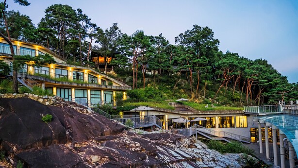 Un hotel moderno con più livelli, terrazze all'aperto e una zona piscina immersa nel verde.