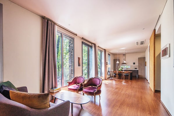 A spacious living area with a sofa, chairs, a dining table, and a kitchen in the background.