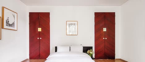 Habitación de hotel con una cama grande, dos armarios, un cuadro enmarcado y un florero con flores.